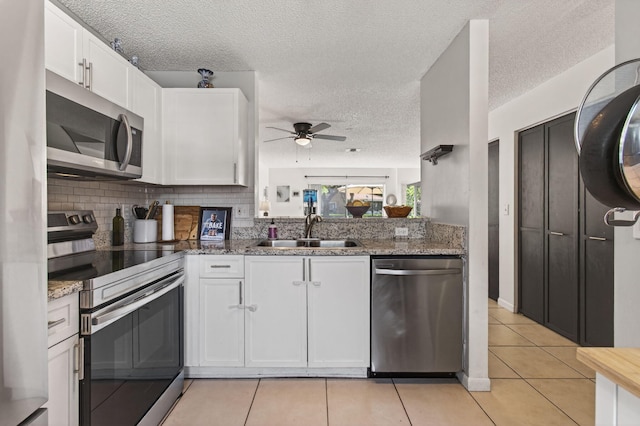 9931 Kamena Cir, Boynton Beach, FL 33436 - kitchen featuring appliances with stainless steel finishes, ceiling fan, white cabinets, a textured ceiling, and light tile patterned flooring