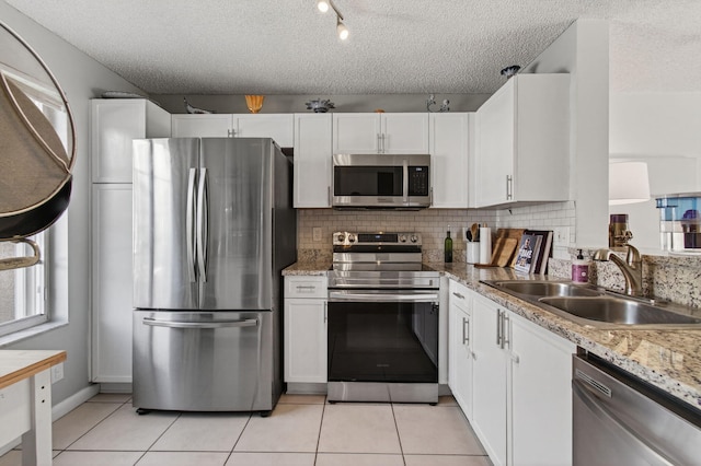 9931 Kamena Cir, Boynton Beach, FL 33436 - kitchen with stainless steel appliances, white cabinetry, tasteful backsplash, light tile patterned floors, and a textured ceiling