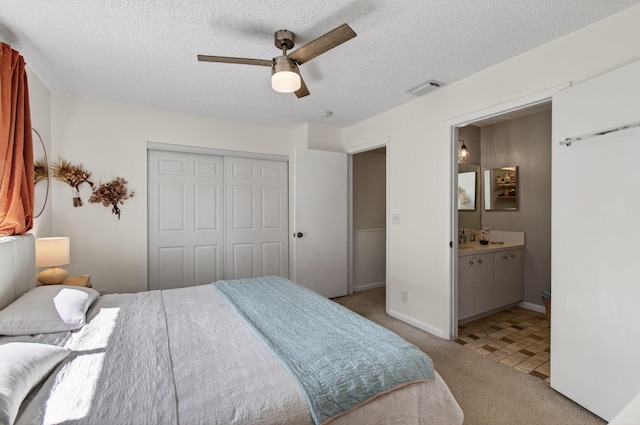 9931 Kamena Cir, Boynton Beach, FL 33436 - bedroom with light carpet, a closet, a textured ceiling, ensuite bathroom, and a ceiling fan