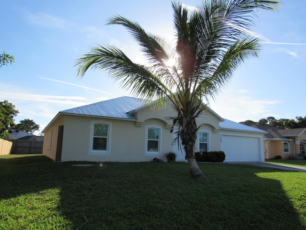 1482 SE Kirke Ln, Port Saint Lucie, FL 34983 - view of front of house featuring stucco siding, a garage, a metal roof, and driveway