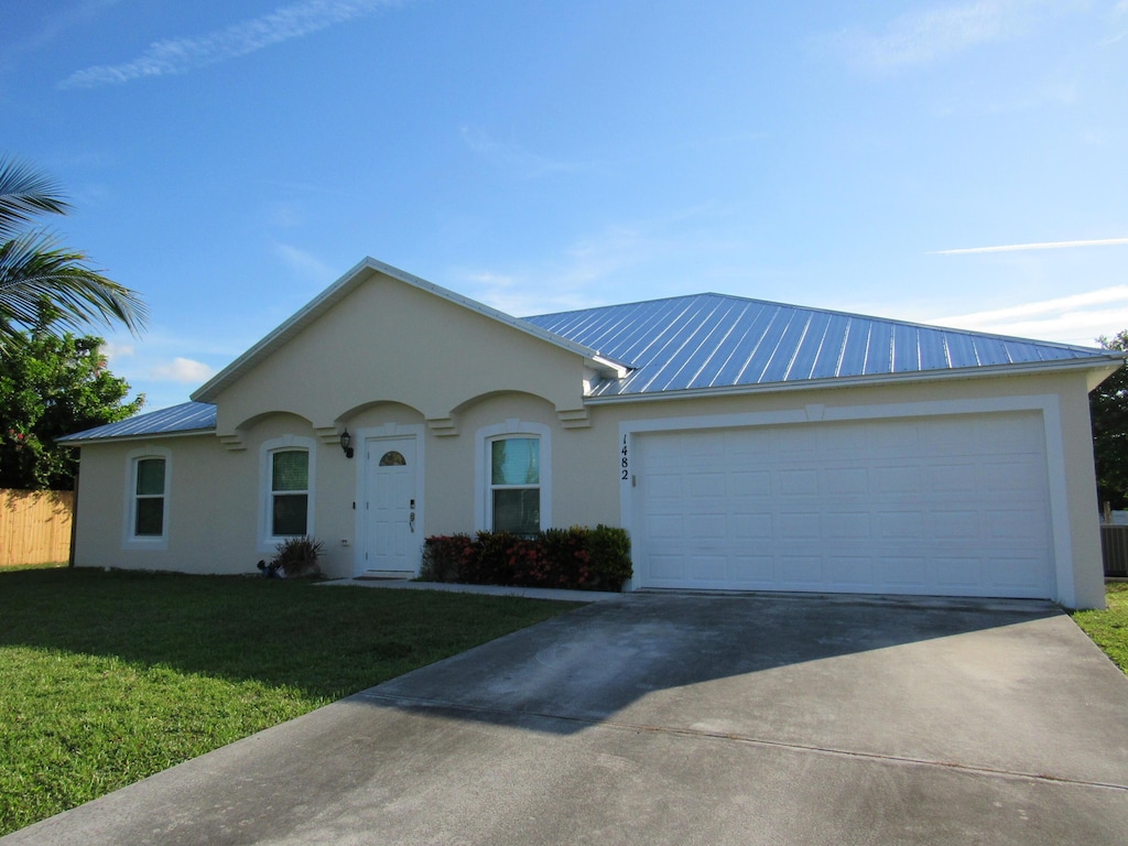 1482 SE Kirke Ln, Port Saint Lucie, FL 34983 - ranch-style house with stucco siding, a metal roof, driveway, and a front yard