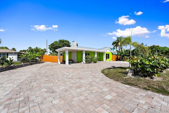 5203 S Indian River Dr, Fort Pierce, FL 34982 - view of front facade with a chimney, curved driveway, a porch, a metal roof, and a standing seam roof