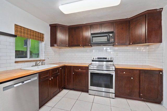5203 S Indian River Dr, Fort Pierce, FL 34982 - kitchen with appliances with stainless steel finishes, light tile patterned floors, decorative backsplash, butcher block counters, and dark brown cabinetry