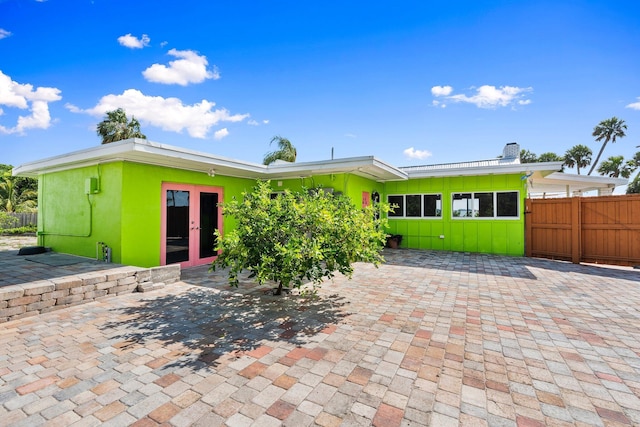 5203 S Indian River Dr, Fort Pierce, FL 34982 - rear view of house featuring french doors, board and batten siding, a chimney, and a patio area