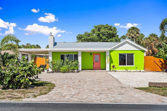 5203 S Indian River Dr, Fort Pierce, FL 34982 - view of front of house featuring a chimney, driveway, a metal roof, and a carport