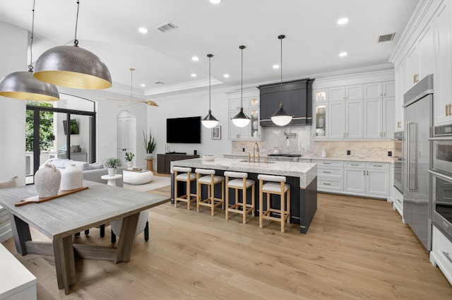 17865 Monte Vista Dr, Boca Raton, FL 33496 - kitchen with backsplash, a breakfast bar area, recessed lighting, white cabinets, and a center island with sink