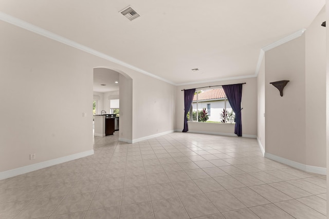 879 SW Pebble Ln, Palm City, FL 34990 - empty room featuring crown molding, plenty of natural light, arched walkways, and light tile patterned floors