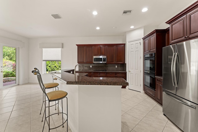 879 SW Pebble Ln, Palm City, FL 34990 - kitchen featuring black appliances, light tile patterned floors, tasteful backsplash, a breakfast bar area, and recessed lighting
