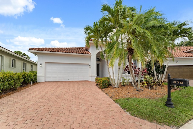 879 SW Pebble Ln, Palm City, FL 34990 - mediterranean / spanish-style house with driveway, a garage, stucco siding, and a tiled roof
