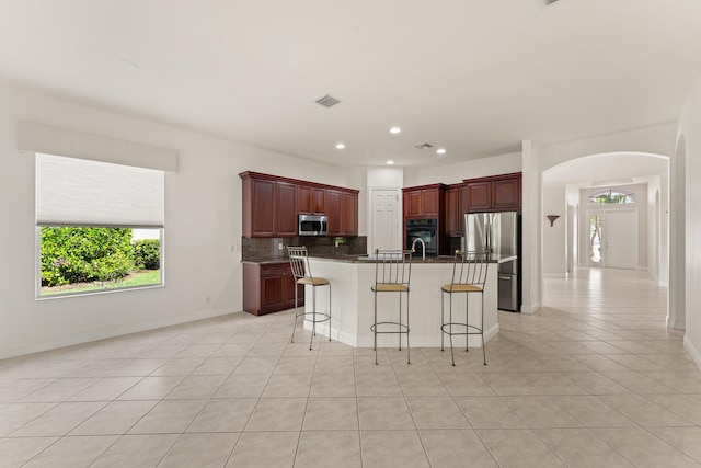 879 SW Pebble Ln, Palm City, FL 34990 - kitchen featuring appliances with stainless steel finishes, arched walkways, decorative backsplash, light tile patterned floors, and recessed lighting