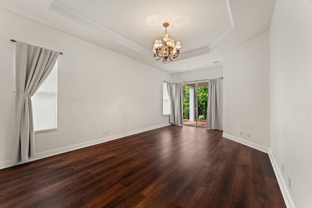 879 SW Pebble Ln, Palm City, FL 34990 - spare room with a tray ceiling, a chandelier, dark wood-style flooring, and ornamental molding