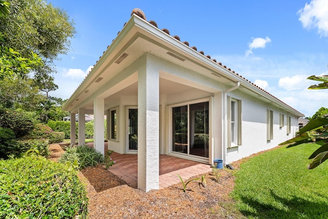 879 SW Pebble Ln, Palm City, FL 34990 - back of property featuring stucco siding, a patio, and a lawn