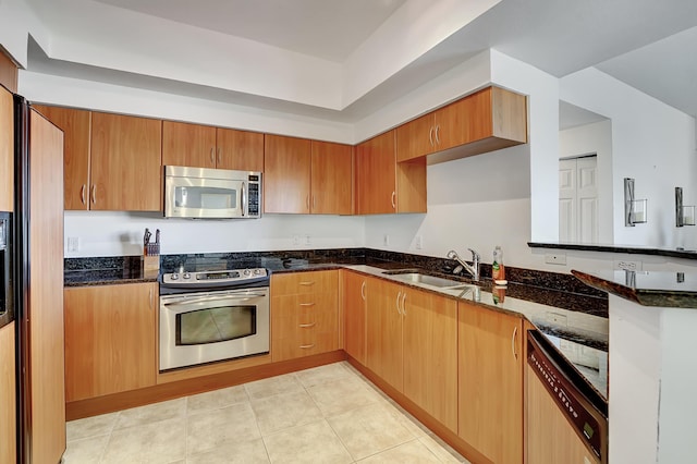 804 E Windward Way Unit 606, Lantana, FL 33462 - kitchen featuring stainless steel appliances, dark stone counters, a peninsula, light tile patterned floors, and brown cabinets
