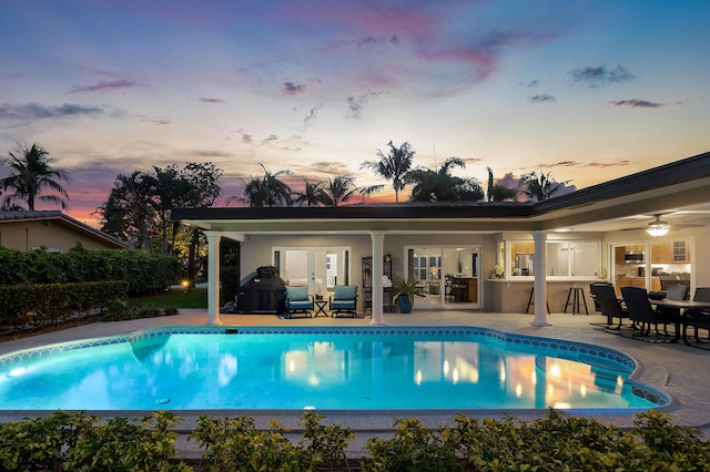 4220 NE 24th Ave, Lighthouse Point, FL 33064 - pool at dusk featuring a patio, an outdoor pool, french doors, and ceiling fan