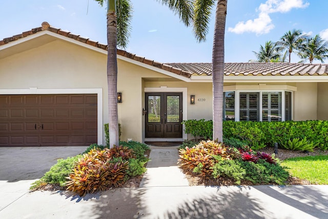 4220 NE 24th Ave, Lighthouse Point, FL 33064 - view of front of property featuring stucco siding, french doors, an attached garage, and a tiled roof