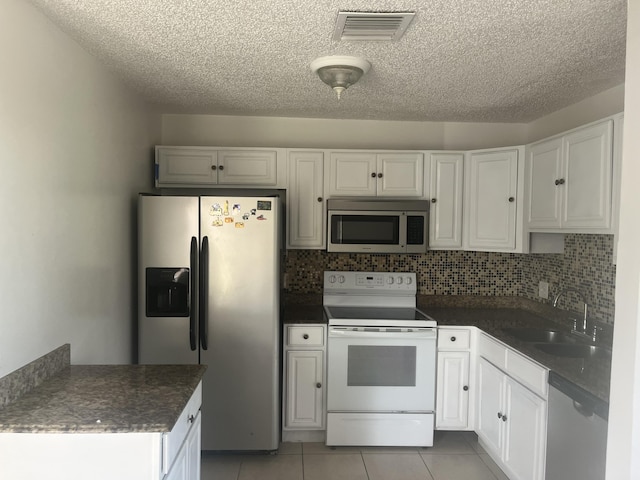 2548 Ida Way Unit 3A, West Palm Beach, FL 33415 - kitchen featuring stainless steel appliances, a textured ceiling, light tile patterned floors, backsplash, and dark countertops