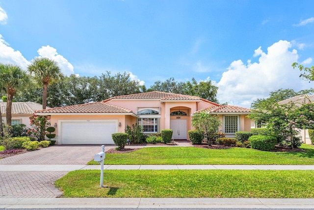 5422 Landon Cir, Boynton Beach, FL 33437 - mediterranean / spanish-style house featuring an attached garage, stucco siding, a tile roof, decorative driveway, and a front lawn