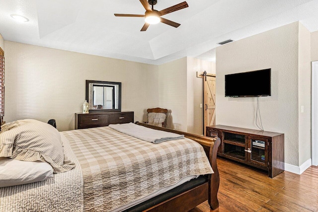 5336 NW 57th Way, Coral Springs, FL 33067 - bedroom with a barn door, wood finished floors, a raised ceiling, and ceiling fan
