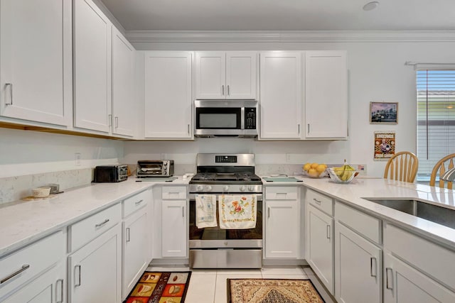 556 SE Mulberry Way, Port Saint Lucie, FL 34984 - kitchen with stainless steel appliances, white cabinetry, light tile patterned floors, ornamental molding, and light stone countertops