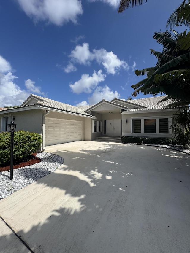 8711 Eagle Run Dr, Boca Raton, FL 33434 - view of front of home featuring a garage, stucco siding, driveway, and a tile roof