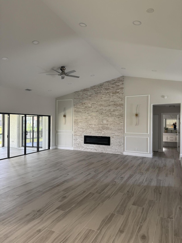 8711 Eagle Run Dr, Boca Raton, FL 33434 - unfurnished living room with vaulted ceiling, a ceiling fan, light wood finished floors, and a stone fireplace