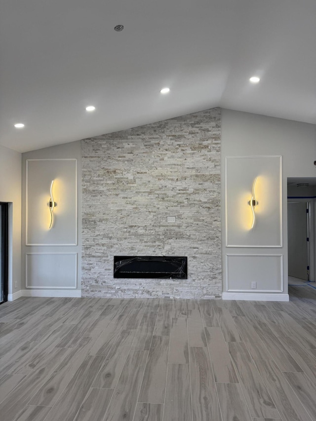 8711 Eagle Run Dr, Boca Raton, FL 33434 - unfurnished living room with vaulted ceiling, wood finished floors, a stone fireplace, and recessed lighting