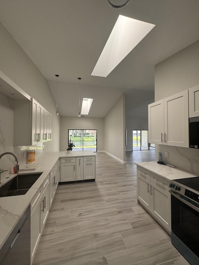 8711 Eagle Run Dr, Boca Raton, FL 33434 - kitchen with stainless steel appliances, a skylight, light stone counters, a peninsula, and vaulted ceiling