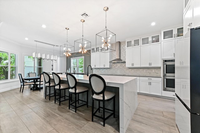 4112 Italia Way, Lake Worth, FL 33467 - kitchen with wall chimney exhaust hood, a chandelier, double oven, a large island with sink, and tasteful backsplash