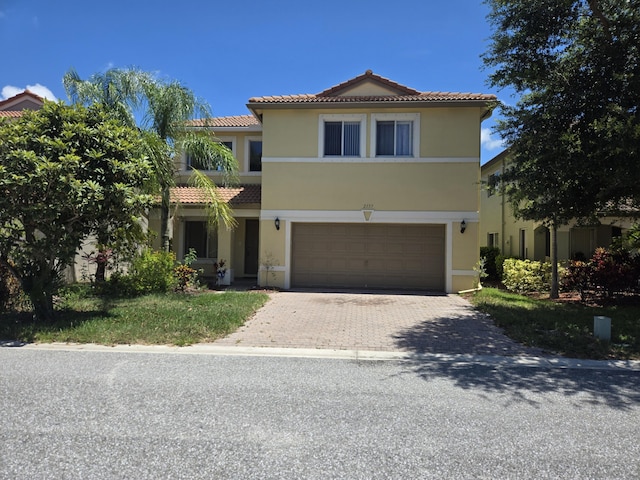 2137 Little Torch St, Riviera Beach, FL 33407 - mediterranean / spanish house featuring a tile roof, an attached garage, stucco siding, and decorative driveway