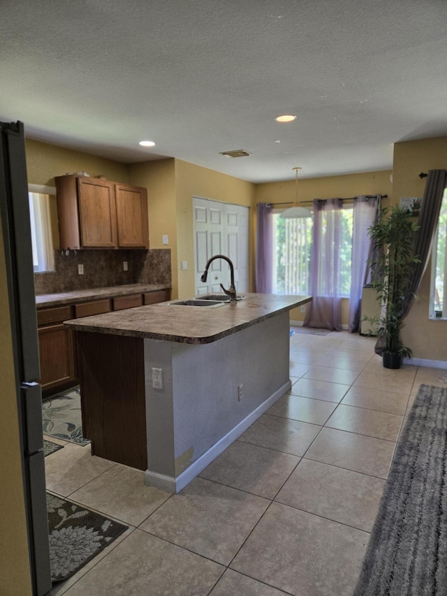 2137 Little Torch St, Riviera Beach, FL 33407 - kitchen with freestanding refrigerator, decorative backsplash, an island with sink, a textured ceiling, and light tile patterned floors