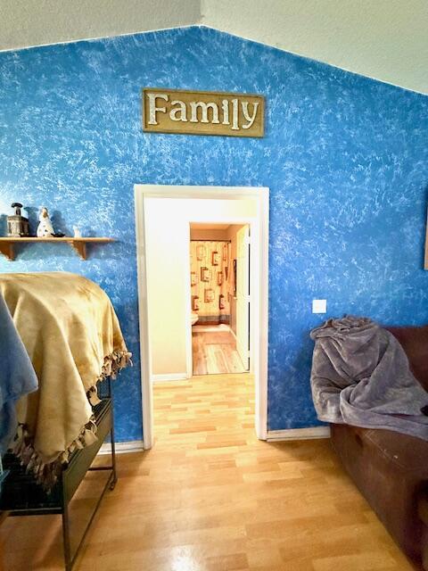 15252 74th St Unit N, The Acreage, FL 33470 - hallway with vaulted ceiling, wood finished floors, and wallpapered walls