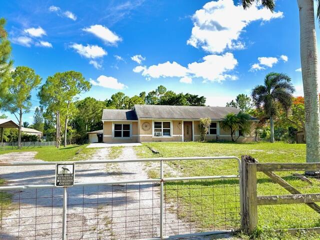 15252 74th St Unit N, The Acreage, FL 33470 - ranch-style home featuring a fenced front yard, a gate, stucco siding, and driveway