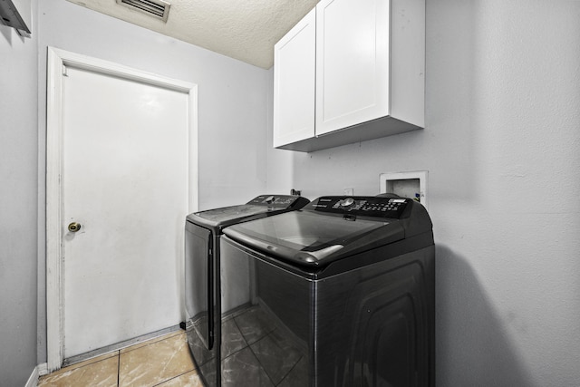 421 NW Cornell Ave, Port Saint Lucie, FL 34983 - laundry area featuring cabinet space, washer and clothes dryer, a textured ceiling, and light tile patterned floors