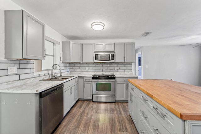 4364 N Mary Cir, Palm Beach Gardens, FL 33410 - kitchen featuring stainless steel appliances, gray cabinetry, wood counters, backsplash, and dark wood-style flooring