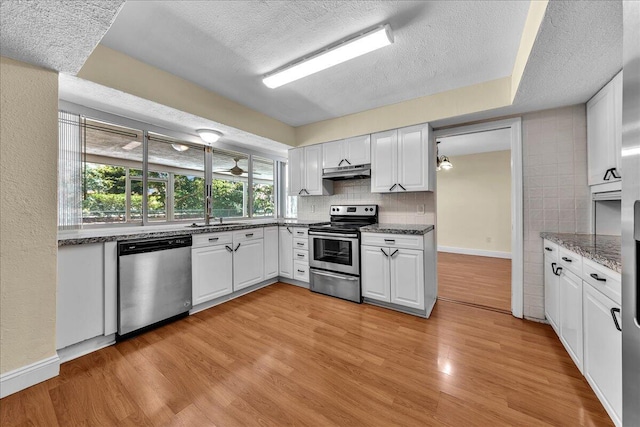 11061 NW 45th St, Coral Springs, FL 33065 - kitchen with appliances with stainless steel finishes, under cabinet range hood, a textured ceiling, white cabinetry, and light wood-type flooring