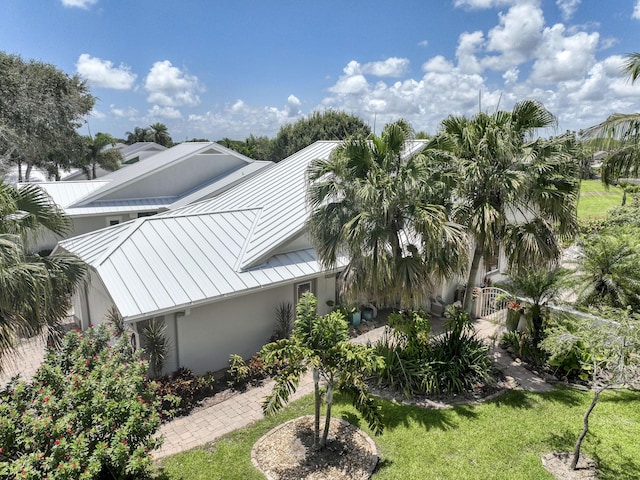 116 Dunes Edge Rd, Jupiter, FL 33477 - view of side of home with a standing seam roof, a metal roof, stucco siding, a gate, and a yard