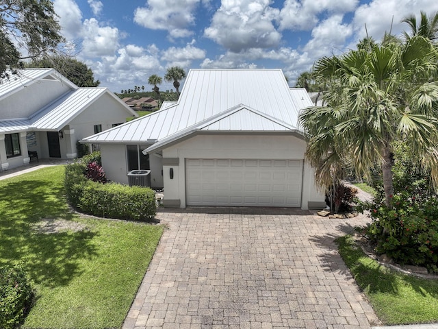 116 Dunes Edge Rd, Jupiter, FL 33477 - view of front of home with a standing seam roof, a metal roof, a garage, a front lawn, and driveway
