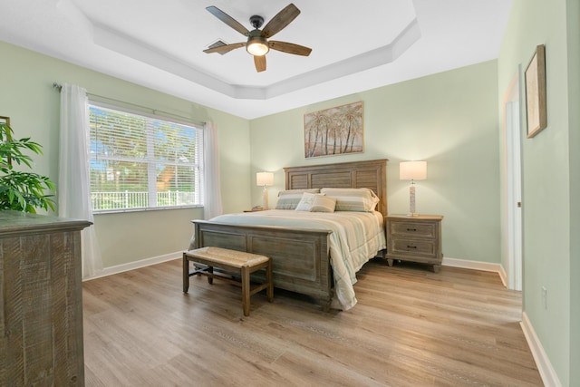 876 SW Rocky Bayou Ter, Port Saint Lucie, FL 34986 - bedroom featuring light wood-type flooring, a tray ceiling, and a ceiling fan