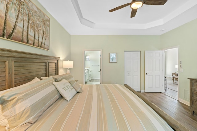 876 SW Rocky Bayou Ter, Port Saint Lucie, FL 34986 - bedroom featuring a raised ceiling, wood finished floors, ensuite bath, ceiling fan, and a closet
