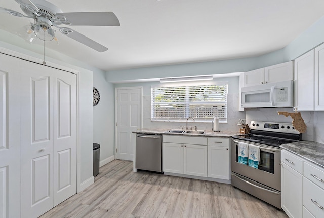 1157 NW 14th Ter, Stuart, FL 34994 - kitchen with appliances with stainless steel finishes, light wood finished floors, white cabinetry, ceiling fan, and light stone countertops