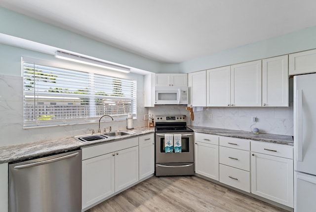 1157 NW 14th Ter, Stuart, FL 34994 - kitchen featuring stainless steel appliances, white cabinetry, healthy amount of natural light, and decorative backsplash