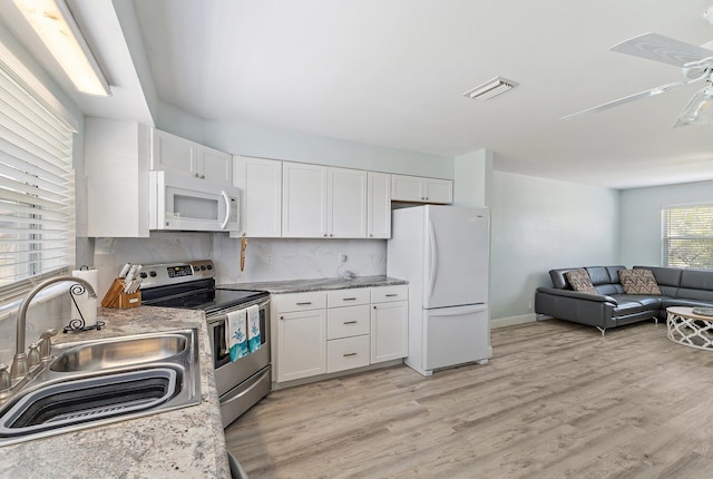 1157 NW 14th Ter, Stuart, FL 34994 - kitchen featuring white appliances, white cabinetry, open floor plan, light wood-type flooring, and backsplash