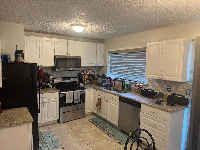 327 NE Surfside Ave, Port Saint Lucie, FL 34983 - kitchen featuring stainless steel appliances, white cabinetry, and a textured ceiling