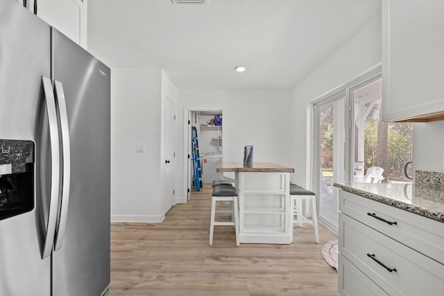 346 Hernando St, Hutchinson Island, FL 34949 - kitchen featuring stainless steel fridge, washer / clothes dryer, light wood-type flooring, light stone countertops, and white cabinetry