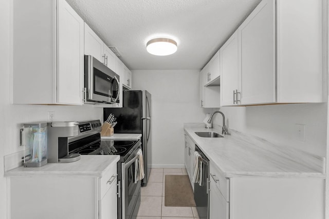 346 Hernando St, Hutchinson Island, FL 34949 - kitchen featuring stainless steel appliances, a textured ceiling, light tile patterned floors, white cabinetry, and light countertops