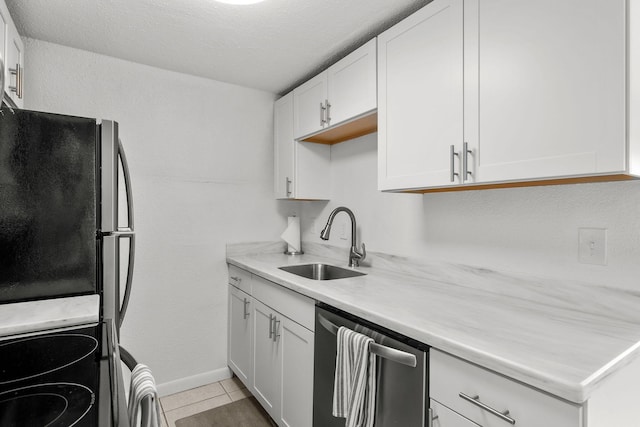 346 Hernando St, Hutchinson Island, FL 34949 - kitchen with stainless steel dishwasher, freestanding refrigerator, light countertops, white cabinets, and light tile patterned floors