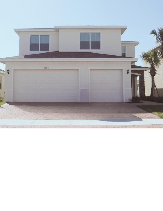 1133 NW Demedici Rd, Port Saint Lucie, FL 34986 - view of front facade featuring a garage, stucco siding, and decorative driveway