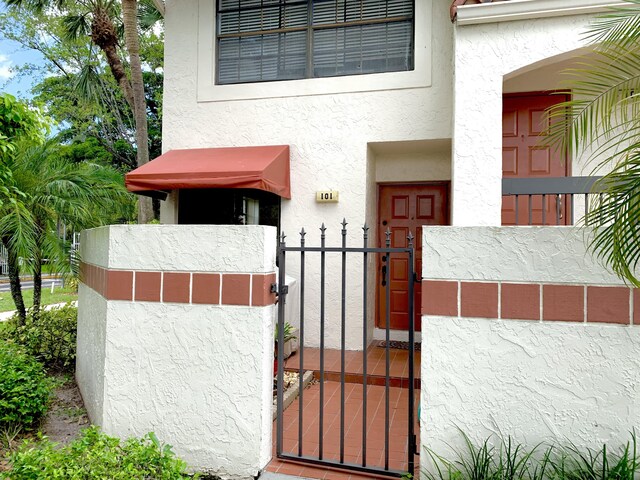 101 Liberty Ct, Deerfield Beach, FL 33442 - property entrance with a gate and stucco siding