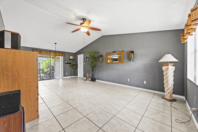 1882 SW Agnes St, Port Saint Lucie, FL 34953 - unfurnished living room with ceiling fan, vaulted ceiling, light tile patterned floors, and a textured ceiling