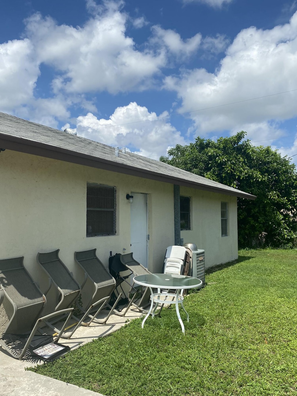 1310 W 24th St, Riviera Beach, FL 33404 - rear view of property with a lawn, stucco siding, and a shingled roof
